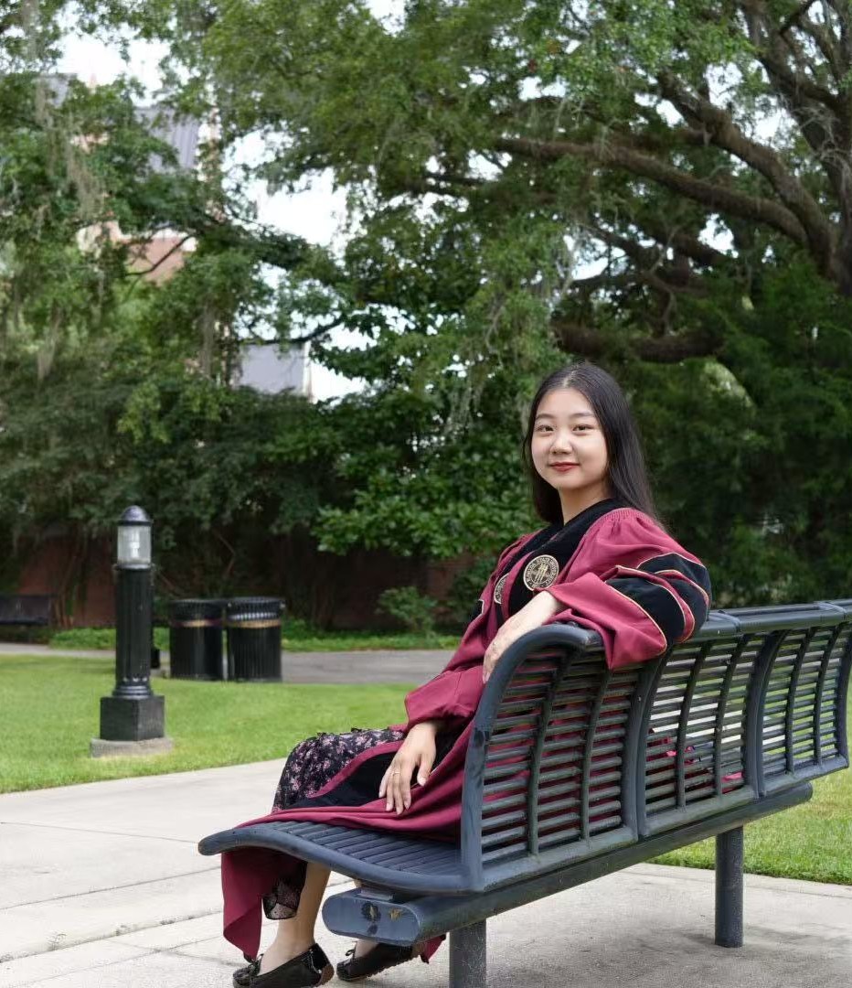 Hui Shi seated outdoors on a university campus